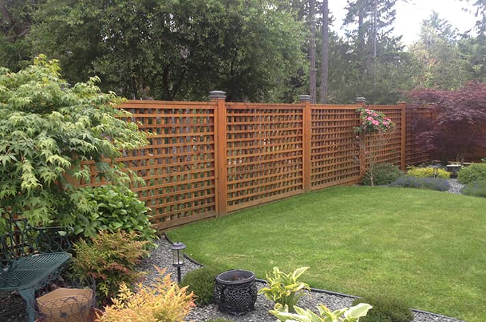 Image of a backyard landscape, including garden beds, lawn, and a custom wood fence