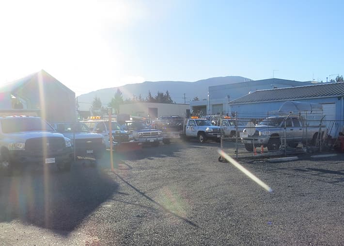 Exterior view of the Acer Landscaping shop compound, with a fleet of dump trucks and other tools
