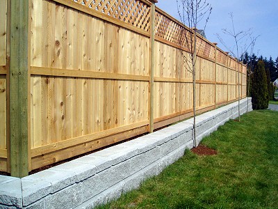 Short Allan Block retaining wall holding up a custom cedar panel fence