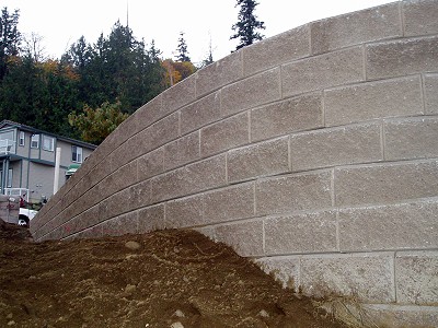 Detail view of a retaining wall being built by Acer Landscaping using grey Allan Block concrete blocks
