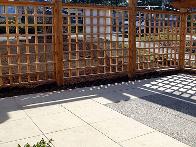 Concrete slab patio with custom cedar lattice surround built by Acer Landscaping