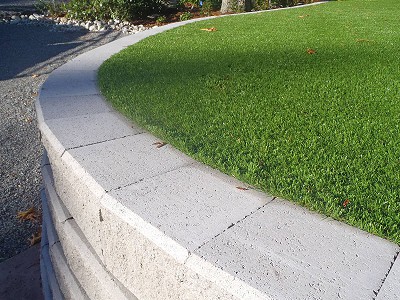 Close-up view of an Allan Block concrete retaining wall holding up a grassed area