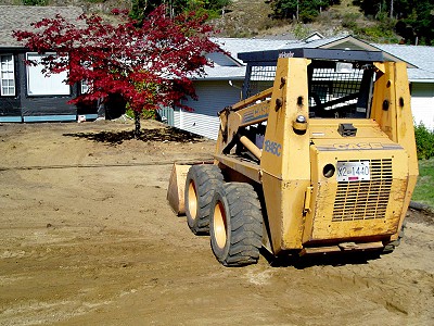 Skid-steer loader owned by Acer Landscaping prepping a front yard for fresh landscaping