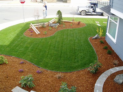 Wide-angle view of a side yard in Nanaimo BC landscaped by Acer Landscaping with a large green lawn area and terraced garden beds