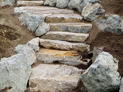 In-progress picture of stairs built from large basalt rocks in a side landscape