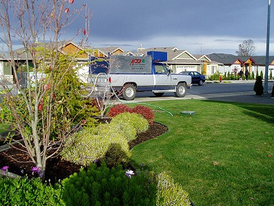 Acer Landscaping work truck in front of a residential yard with air compressor hoses running to an irrigation box for a Winter blow-out