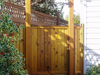 Pathway to a residential backyard with a custom wooden arbor and fence built by Acer Landscaping