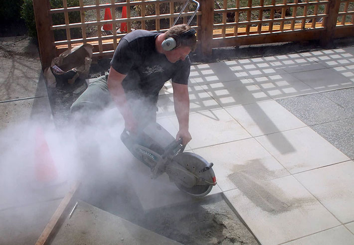 Steve Woodhouse, owner of Acer Landscaping, cutting concrete slabs with a gas powered saw